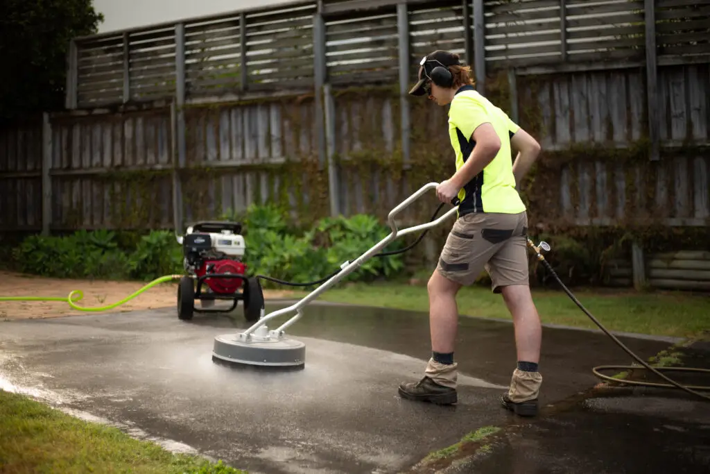 man pressure washing driveway